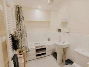 a white bathroom with a tub and a sink at 5 Mariners Wharf in Newhaven +28 photos