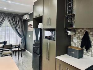 a kitchen with a refrigerator and a dining room at 16 on Les De Jager in Pietermaritzburg