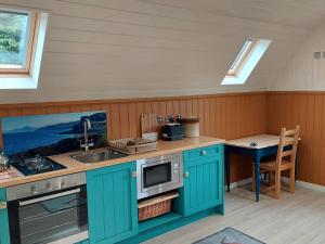 een keuken met blauwe kasten en een wastafel bij Bonnie Wee Neuk in Arbuthnott