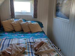 een slaapkamer met een bed met kussens en een raam bij Bonnie Wee Neuk in Arbuthnott