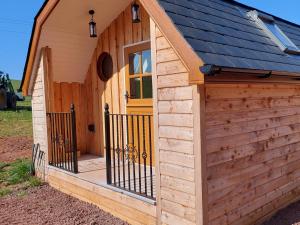 een houten schuur met een veranda en een deur bij Bonnie Wee Neuk in Arbuthnott