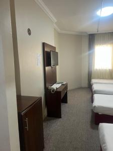 a room with several beds and a desk with a television at فندق منارة العزيزية in Al Gharīth