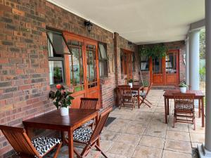 a patio with tables and chairs and a brick wall at Tambula Guest House in Cape Town