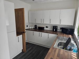 a kitchen with white cabinets and a sink at 58 Clifton Rise in Abergele