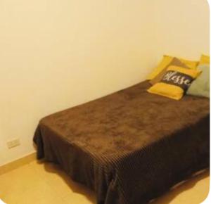una camera da letto con un letto con una coperta marrone e cuscini di Jujuy internacional AirPort a El Carmen Altre 5 foto