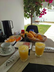 een tafel met sinaasappelsap en een fruitmand bij Suíte Praia do Peró in Cabo Frio