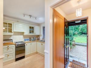 a kitchen with white cabinets and an open door at River View in Wadebridge