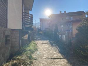 Eine Person, die auf einem unbefestigten Weg neben einem Gebäude entlanggeht in der Unterkunft Студио за гости Петрови in Bansko + 94 Fotos