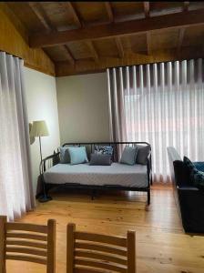 a bedroom with a bed and a couch in front of a window at Chalé de montanha com Lareira in Vieira do Minho