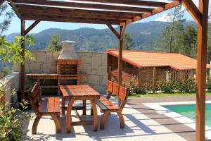 a wooden table and chairs on a patio with a fireplace at Chalé de montanha com Lareira in Vieira do Minho