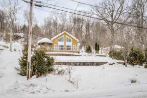 ein gelbes Haus mit Schnee auf dem Boden in der Unterkunft Spa Lake - Naturo lac Sept-Iles in Saint-Raymond