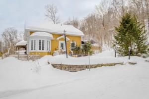 ein gelbes Haus mit Schnee auf dem Boden in der Unterkunft Spa Lake - Naturo lac Sept-Iles in Saint-Raymond