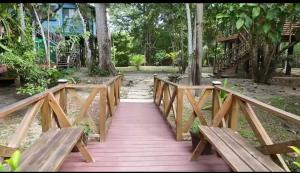 a wooden bridge in a park with two benches at The Howler Jungle House and Cabanas in Belize City