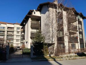 ein Mehrfamilienhaus mit einem Zaun davor in der Unterkunft Студио за гости Петрови in Bansko