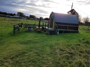 a barn with a table and a bench in a field at St Austell Glamping in Lanivet