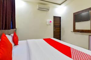 una camera da letto con un letto con cuscini rossi e una TV di Hotel O Pink Orchid a Kota Altre 26 foto