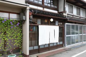a building with a window with a white curtain on it at Guest House Ui-ca in Kanazawa
