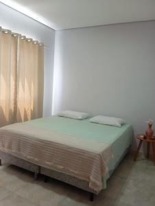 een bed in een witte kamer met gordijnen en een tafel bij Pousada Flor de Caroá in Piranhas