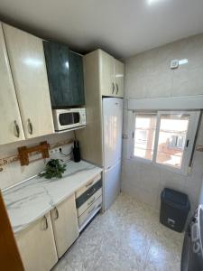a kitchen with a white refrigerator and a window at Piso en Calle Albares De La Ribera in Madrid