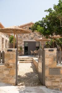 a stone house with an open gate and umbrella at petra apartments apartment No3 in Methoni +41 photos