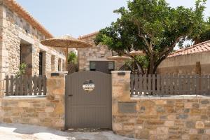 a stone house with a gate and an umbrella at petra apartments apartment No3 in Methoni