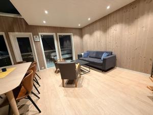 a living room with a couch and a table and chairs at Finnvika panorama Cabin 2 in Vestvågøya +15 photos