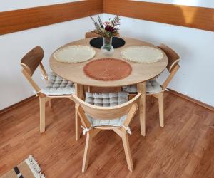 a wooden table with chairs and a vase with flowers at Apartmán v centre Donovaly s garážou in Donovaly
