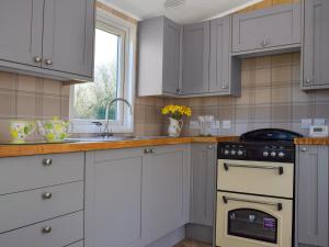 a kitchen with white cabinets and a sink and an oven at Owl Lodge - Uk49144 in Hartshorne