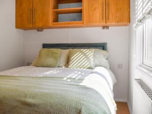 a bed in a bedroom with wooden cabinets at Owl Lodge - Uk49144 in Hartshorne +9 photos