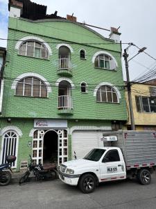 een witte vrachtwagen geparkeerd voor een groen gebouw bij Ayenda Marana in Manizales