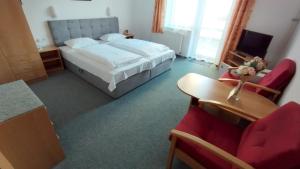 een hotelkamer met een bed, een bureau en stoelen bij Penzion U Pošty Blatná in Strakonice +6 foto's