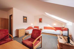een hotelkamer met twee bedden en een stoel bij Penzion U Pošty Blatná in Strakonice +6 foto's