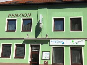 een groen gebouw met een bord ervoor bij Penzion U Pošty Blatná in Strakonice