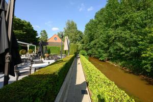 een rivier met bankjes en parasols ernaast bij Le Mirage De Watermolen Kasterlee in Kasterlee