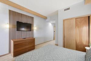 een slaapkamer met een bed en een televisie aan de muur bij 233B Beachside Hideaway | European Village in Bon Terra