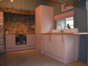 a kitchen with white cabinets and a sink and a window at Ty Llaeth in Llanstephan
