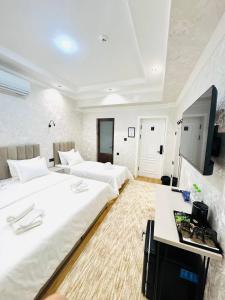 een slaapkamer met twee bedden en een bureau erin bij The Moonya Hotel in Samarkand