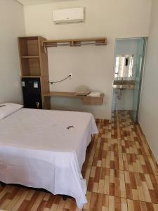 a bedroom with a white bed and a glass door at Hotel Apis Silvestre in Cruzeiro da Fortaleza