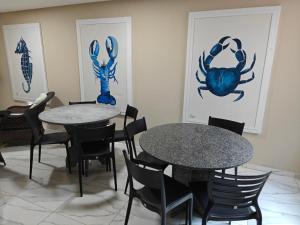 two tables and chairs in a room with paintings at Pousada Porto Meu Amor in Porto De Galinhas