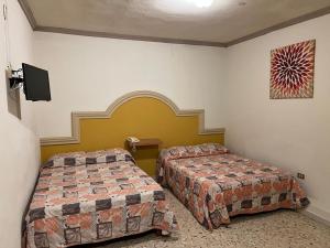 een kamer met twee bedden en een tv aan de muur bij Hotel y Restaurant Real Plaza Jacona in Ciudad Valles +1 foto