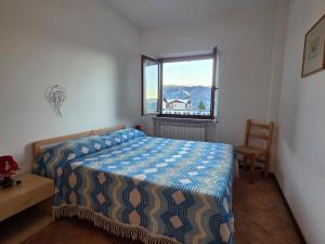 a bedroom with a bed and a window and a chair at Casa Giardina-bilocale con deposito biciclette-sci in San Giacomo