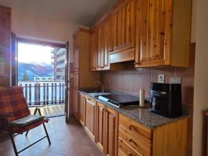 a kitchen with wooden cabinets and a sink and a balcony at Casa Giardina-bilocale con deposito biciclette-sci in San Giacomo