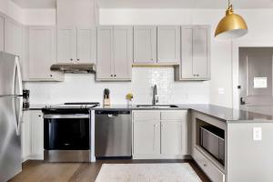 a kitchen with white cabinets and stainless steel appliances at Fire Tower Downtown Gem 1BR with Balcony & Views in Charleston