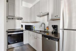 a kitchen with white cabinets and a stainless steel refrigerator at Fire Tower Luxe 2BR KingSuites & Private Balcony in Charleston
