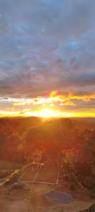 einen Tennisplatz mit Sonnenuntergang im Hintergrund in der Unterkunft Chalé Bela Vista in Munhoz