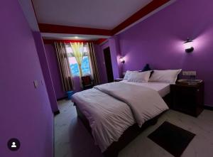 a bedroom with purple walls and a large bed at Tashidelk homestay in Darjeeling