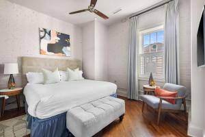 a white bedroom with a large bed and a chair at Perfect Location - King Street Condo in Charleston +5 photos