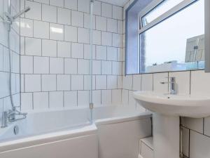 a white tiled bathroom with a sink and a bath tub at 4 Bed in Seascale oc-85807 in Gosforth +17 photos