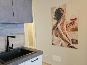 a kitchen with a painting of a woman holding a glass of wine at Moda Apartments 47 in Sestriere