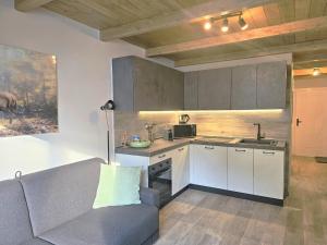 a kitchen with white cabinets and a couch in a room at Moda Apartments 47 in Sestriere